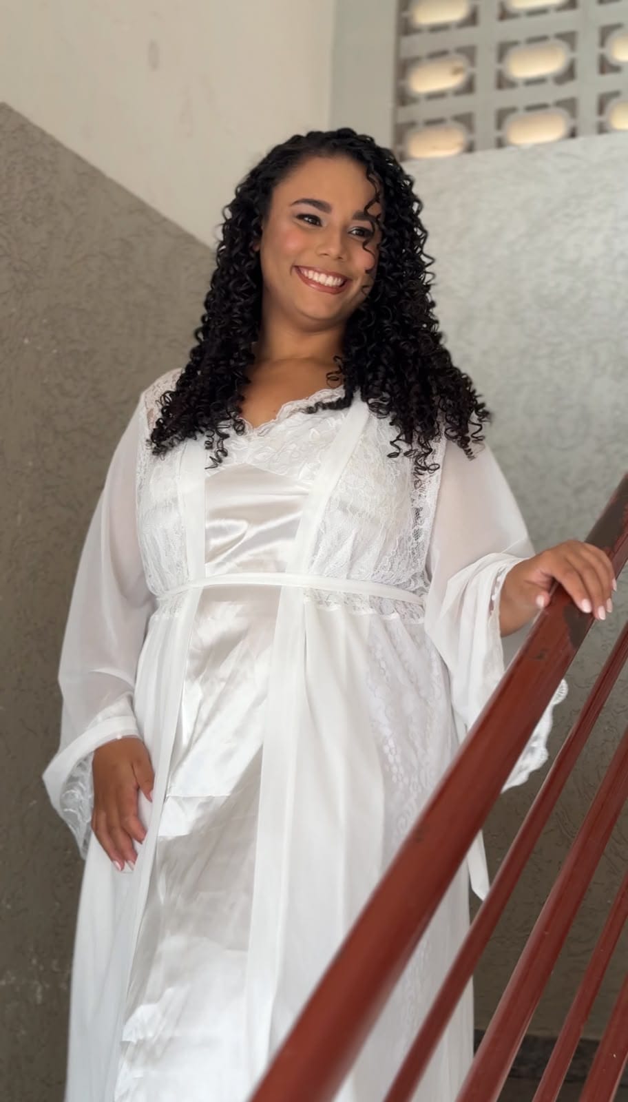 Noiva de robe sorrindo na escada, no making of do casamento
